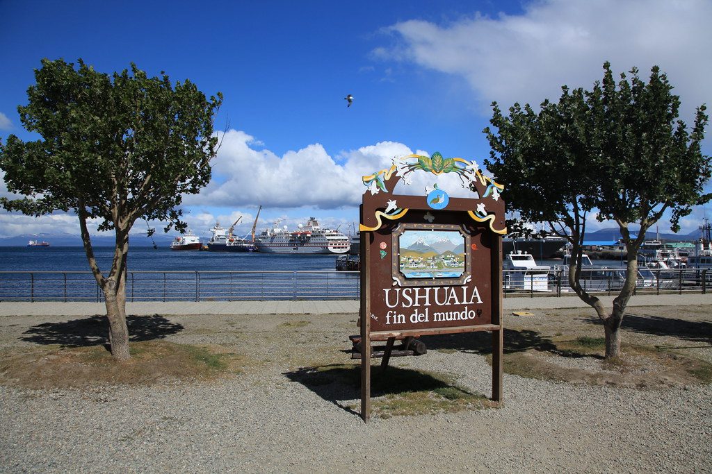 Указатель Ushuaia Fin del Mundo на набережной с круизными судами на канале Бигля