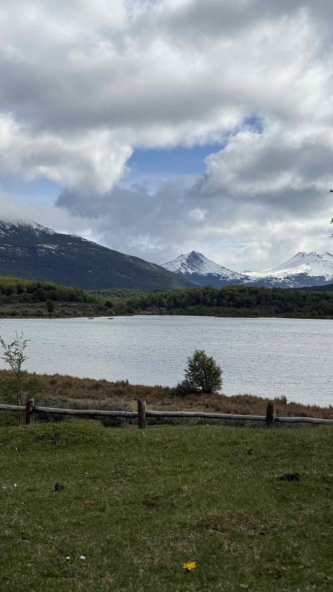Горное озеро в парке Tierra del Fuego с заснеженными вершинами и деревянной оградой