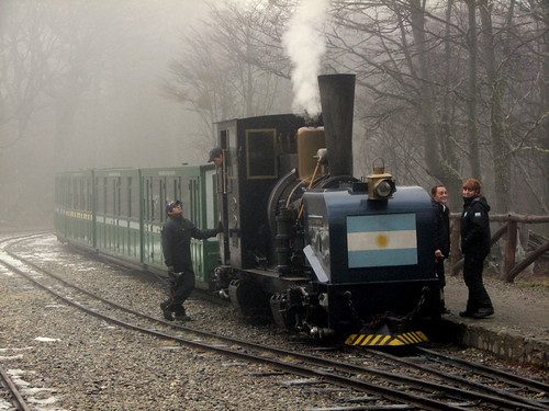 Паровоз Tren del Fin del Mundo с аргентинским флагом и гидом в туманном лесу ленга